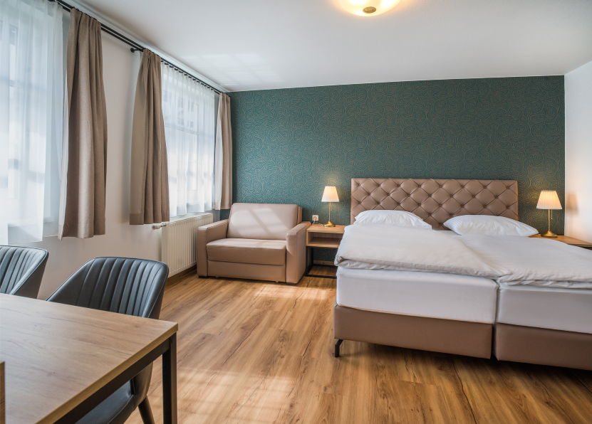 Modernes Hotelzimmer mit gepolstertem Bettkopfteil, Couch und Nachtkästchen