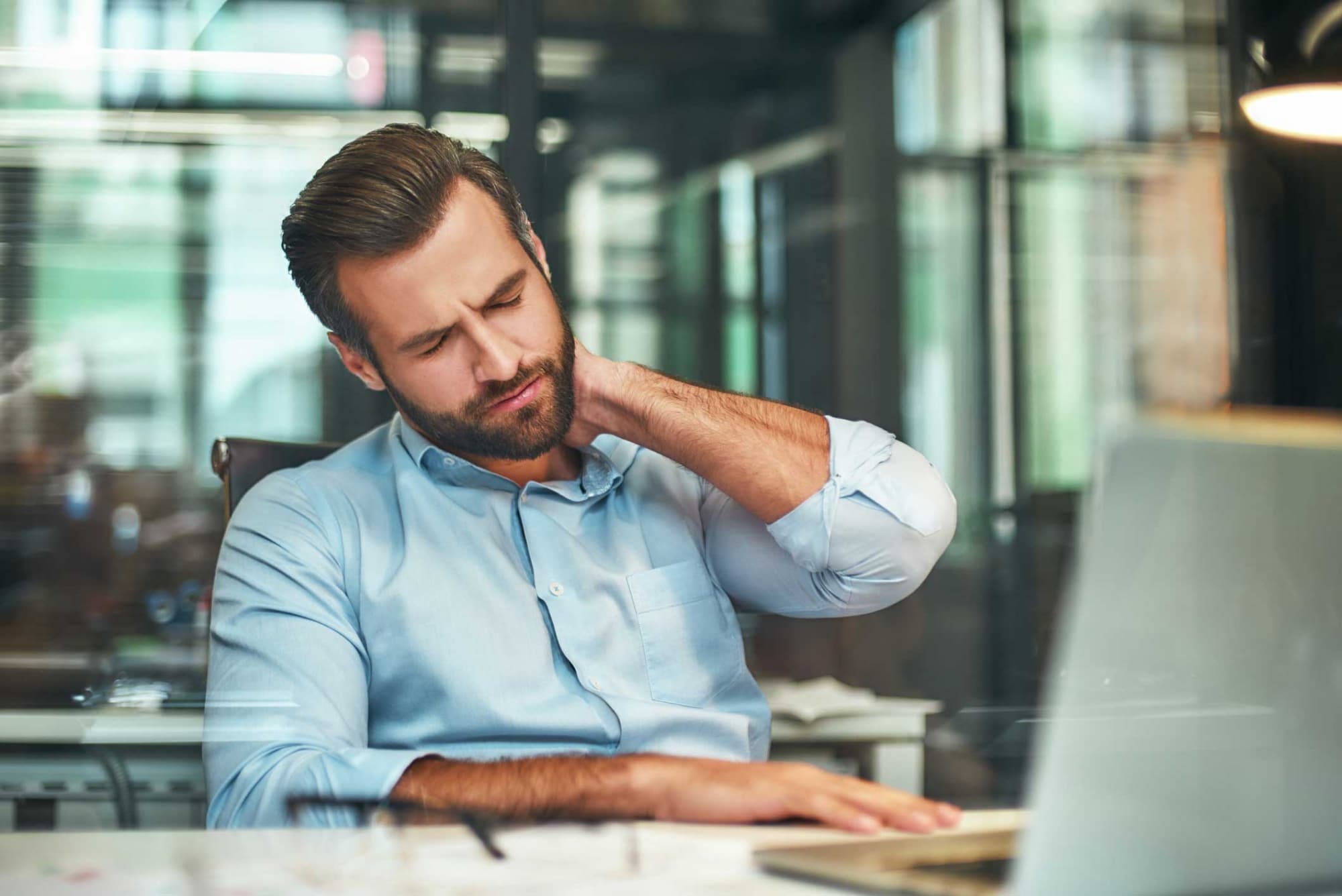 Mann mit Rückschmerzen durch schlechte Haltung im Büro