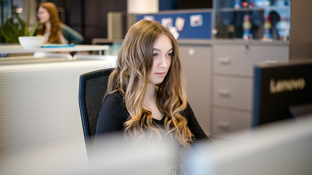 hali Lehrling arbeitet konzentriert am Laptop im modernen Büro