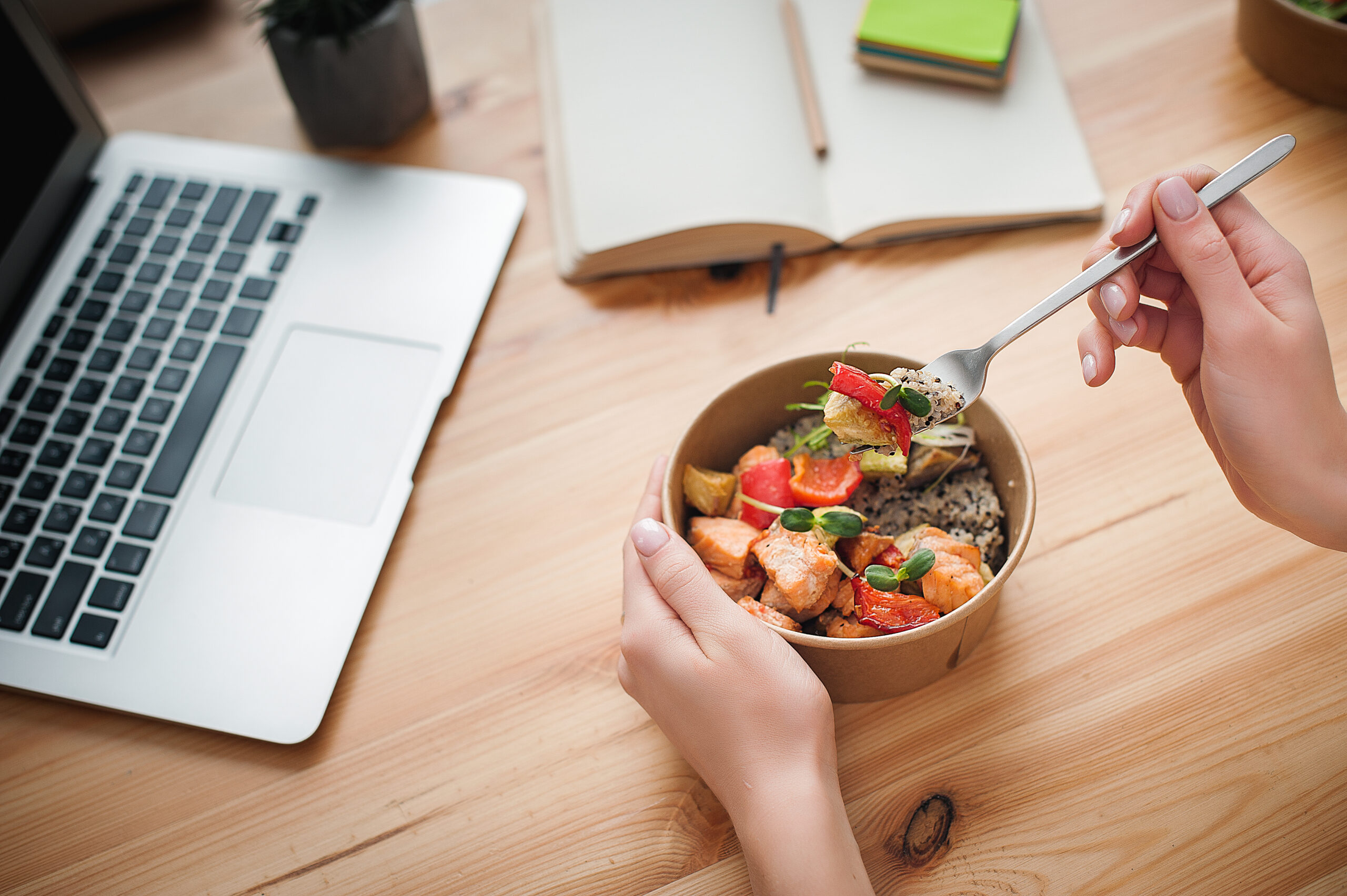 Frau isst gesundes Mittagessen am Laptop im Homeoffice